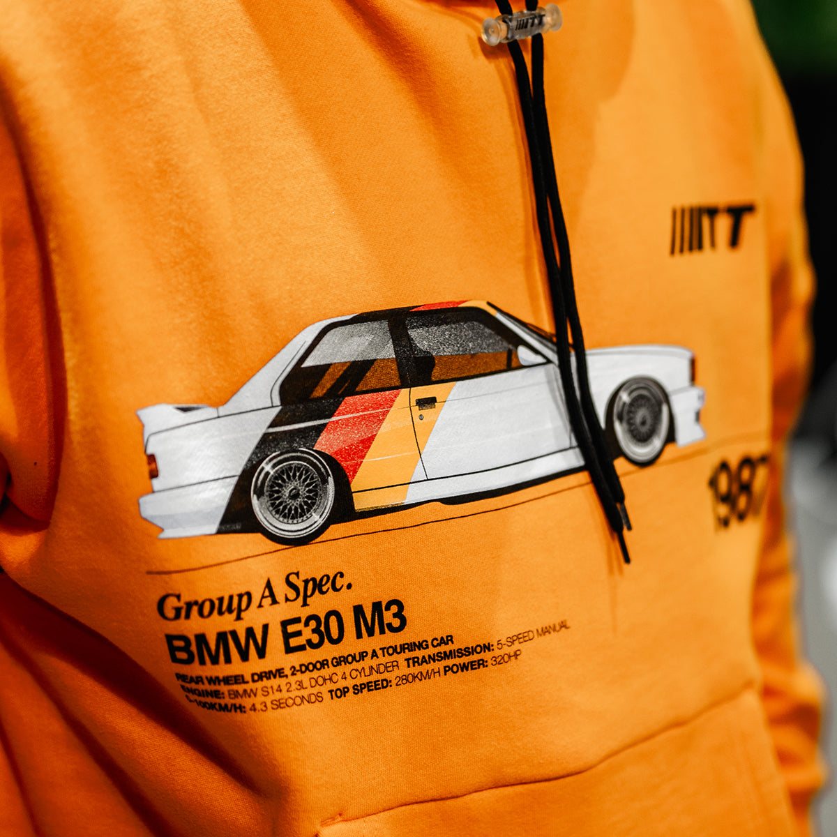 Close up shot of Turbo Threads scarlet orange standard fit hoodie with a BMW E30 M3 graphic and black text